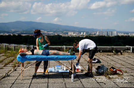 Professional body artist Dino Helvida (R), 27, and his girlfriend Zorana Unkovic (C), 27, prepare Kaitlin, 28, from the United States for body suspension in Zagreb, Croatia June 7, 2016. REUTERS/Antonio Bronic