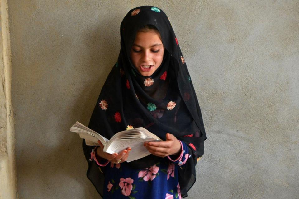 An Afghan girl reads a book inside a one-classroom private educational center in Panjwai district of Kandahar (AFP via Getty Images)