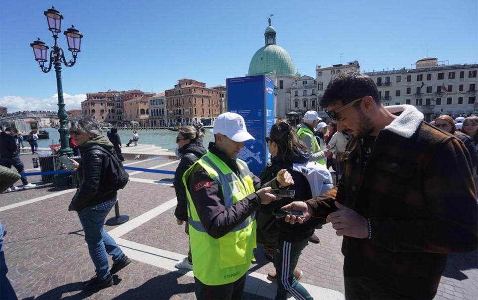 A steward checks tickets as peple enter the city of Venice