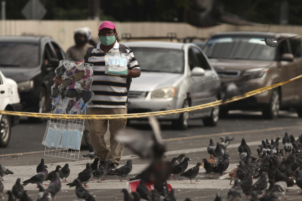 A vendor hawks protective face masks as he walks along Gerardo Barrios Square in San Salvador, El Salvador, Friday, Aug. 7, 2020, amid the new coronavirus pandemic. For months, the strictest measures confronting the COVID-19 pandemic in Latin America seemed to keep infections in check in El Salvador, but a gradual reopening combined with a political stalemate has seen infections increase nearly fourfold. (AP Photo/Salvador Melendez)