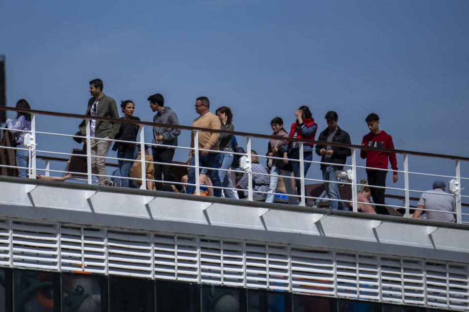 Passengers are photographed on the cruise ship MSC Armony, moored in the port of Barcelona, Spain, Wednesday, April 3, 2024. Authorities said Wednesday that a group of 69 Bolivians are not being allowed to disembark from a cruise ship in the Spanish northeastern port of Barcelona because they lack valid documents to enter the European Union's Schengen area. (AP Photo/Emilio Morenatti)