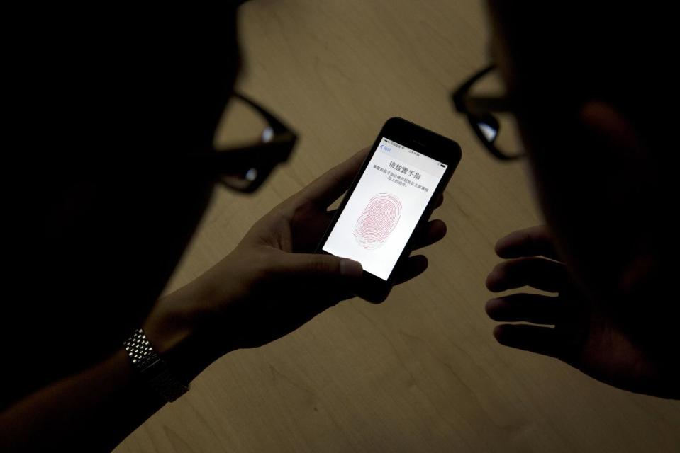 CORRECTS TO U.S. CUSTOMS AND BORDER PROTECTION, NOT PATROL - FILE - In this Sept. 11, 2013, file photo, an Apple employee, right, instructs a journalist on the use of the fingerprint scanner technology built into the company's iPhone 5S during a media event in Beijing. Watchdog groups that keep tabs on digital privacy rights are concerned that U.S. Customs and Border Protection agents are searching the phones and other digital devices of international travelers at border checkpoints in U.S. airports. The American Civil Liberties Union and the Electronic Frontier Foundation say complaints of such searches have spiked recently. (AP Photo/Ng Han Guan, File)