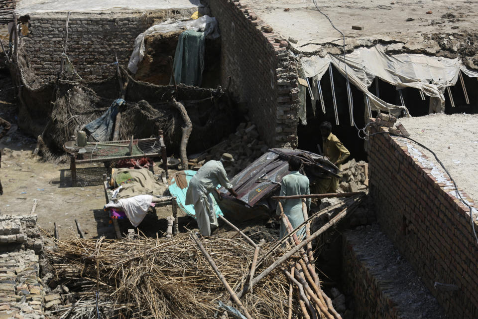 A family salvages belongings from their flood-hit home in Shikarpur district of Sindh province, of Pakistan, Wednesday, Aug. 31, 2022. Officials in Pakistan raised concerns Wednesday over the spread of waterborne diseases among thousands of flood victims as flood waters from powerful monsoon rains began to recede in many parts of the country. (AP Photo/Fareed Khan)