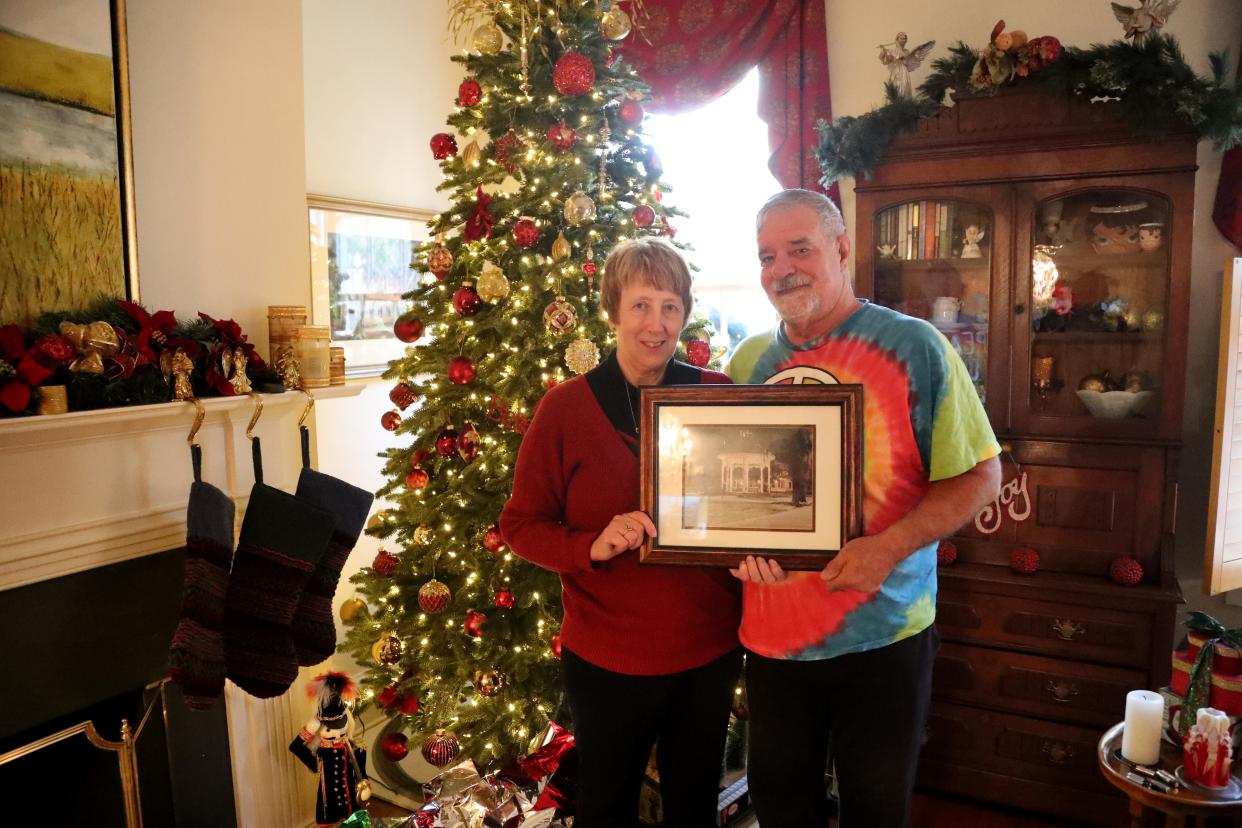 Kristin Lee stands with husband Randy Hobbs as they hold a photo taken by her deceased husband Larry Lee in December 1989.