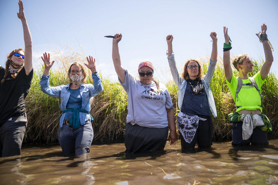 Everlasting Wind, aka Dawn Goodwin, joins others by raising her fist in the Mississippi River near an Enbridge pipeline construction site, on Monday, June 7, 2021, in Clearwater County, Minn., to protest the construction of Enbridge Line 3. Goodwin is a co-founder of RISE Coalition. More than 2,000 Indigenous leaders and "water protectors" gathered in Clearwater County from around the country. The day started with a prayer circle and moved on to a march to the Mississippi headwaters where the oil pipeline is proposed to be built. (Alex Kormann/Star Tribune via AP)