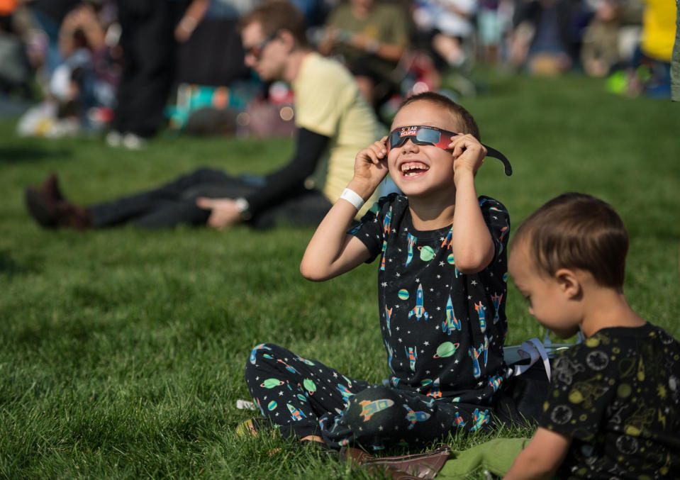 A boy watches the total solar eclipse through protective glasses in Madras, Oregon, on Aug. 21, 2017. <cite>Aubrey Gemignani/NASA</cite>