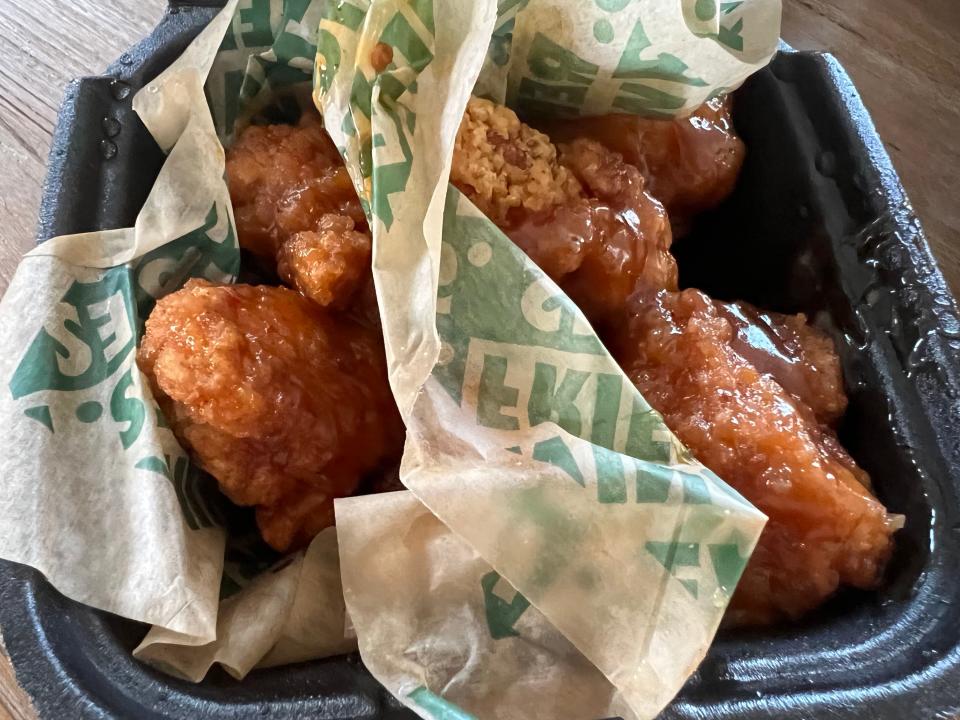 Boneless wings in a to-go box with Wingstop paper separating two different types of wings