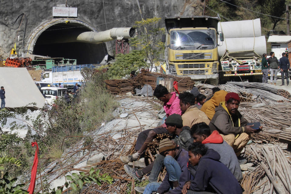 People sit near the site of an under-construction road tunnel that collapsed trapping 41 workers in Silkyara in the northern Indian state of Uttarakhand, Wednesday, Nov. 22, 2023. The workers have been trapped for over a week, as rescuers work on an alternate plan of digging toward them vertically. (AP Photo)