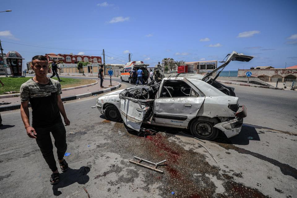 People inspect a damaged car after Israeli warplanes hit coastland in Gaza City, Gaza on May 17, 2021.