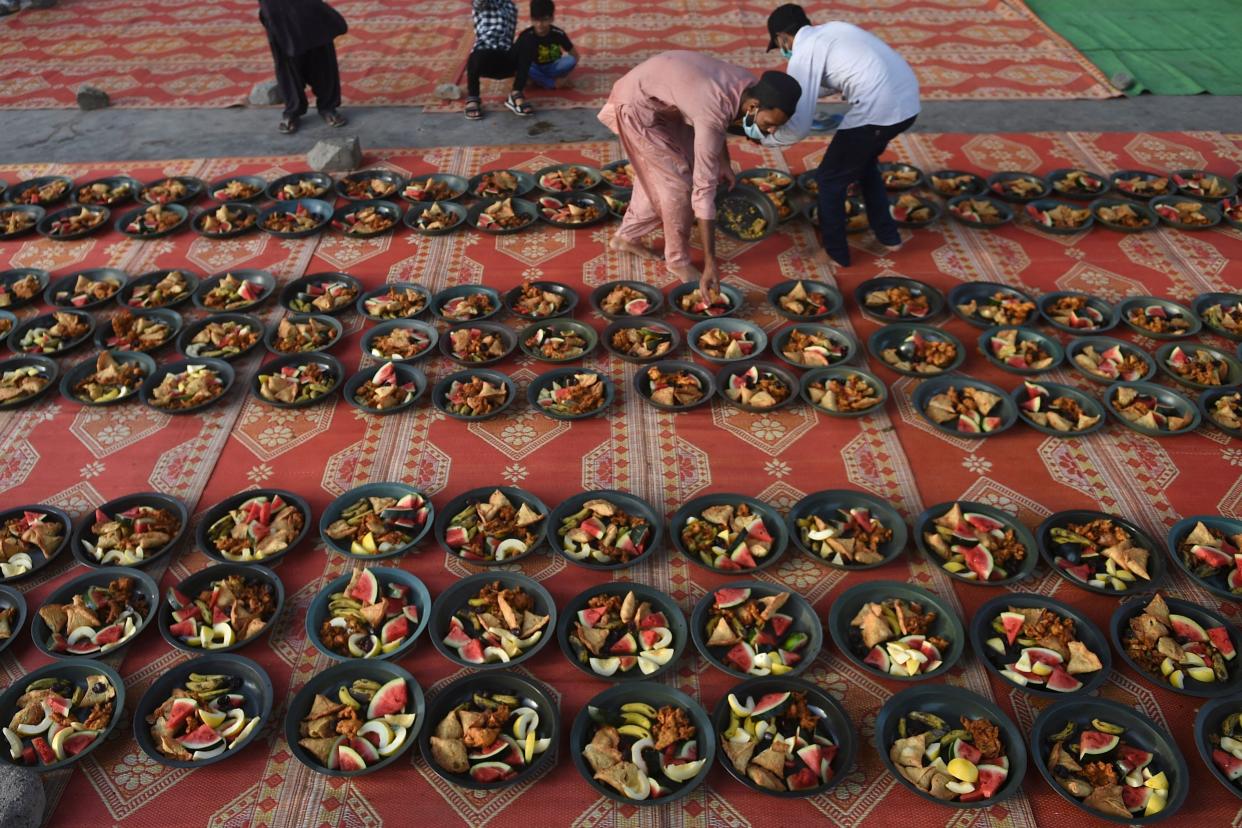 Volunteers prepare Iftar food plates for Muslim devotees to break their fast during the holy month of Ramadan along a street in Karachi on April 23, 2021.
