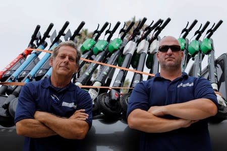 Scoot Scoop founders John Heinkel and Dan Borelli, two professional repo men who have formed a company that acts on behalf of business owners and landlords, pose for a picture next to a truck full of impounded scooters in San Diego , California