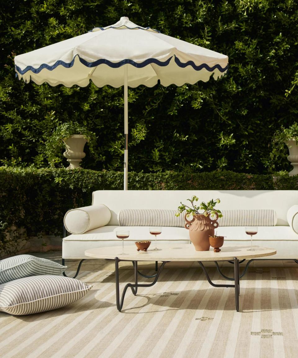 Patio with striped rug and white sofa and sun umbrella