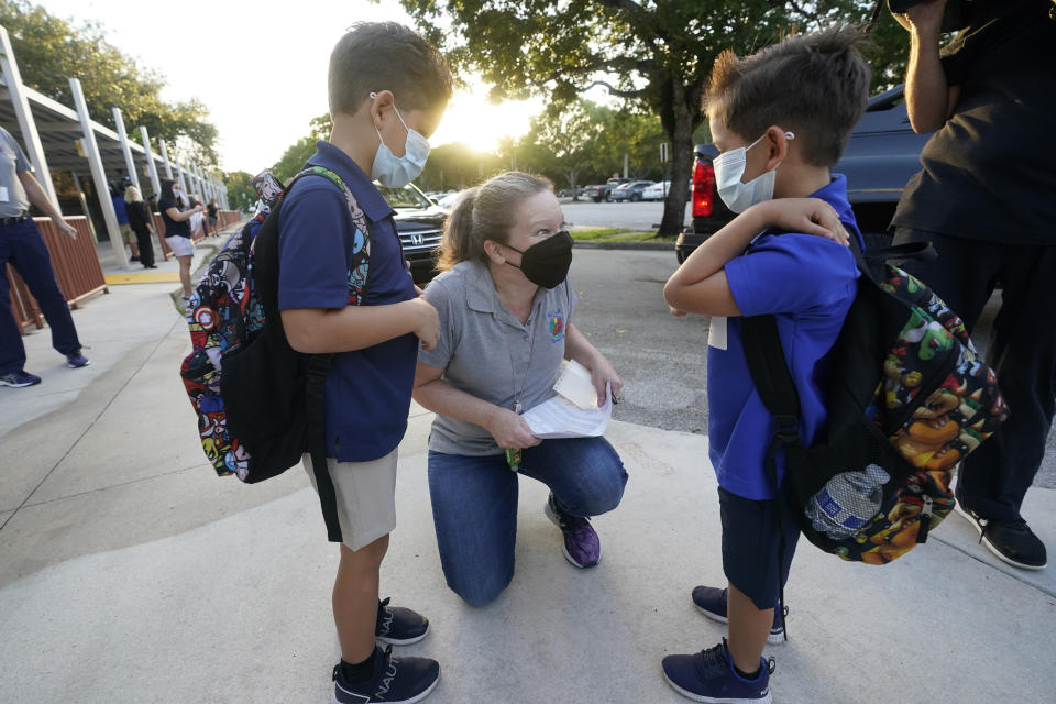 Juliana Orosi, center, checks in students Thomas, left, and Ethan Guillen on the first day of Broward County, Florida schools phased reopening for face-to-face eLearning at Fox Trail Elementary School, on Oct. 9, 2020, in Davie, Fla. (Wilfredo Lee/AP)