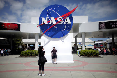 FILE PHOTO: Tourists take pictures of a NASA sign at the Kennedy Space Center visitors complex in Cape Canaveral, Florida April 14, 2010. REUTERS/Carlos Barria