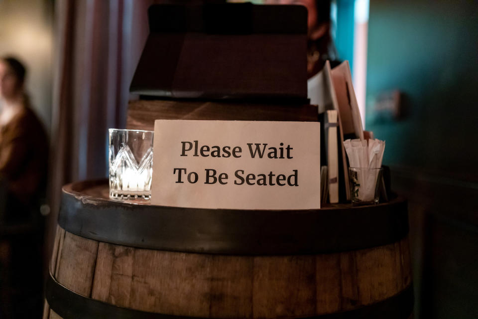 Posted sign on a hostess stand read &quot; Please Wait to be seated&quot;