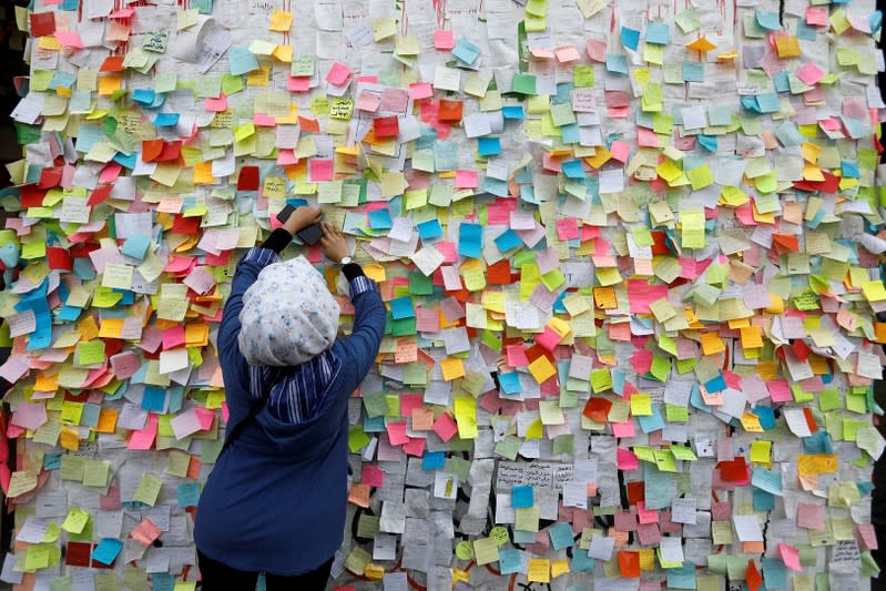 An Iraqi woman demonstrator pastes a note with her wish at a wall of wishes, during ongoing anti-government protests, at the building called 'the Turkish Restaurant Building', in Baghdad