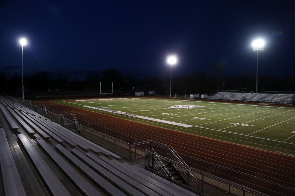 The lights shine on an empty football stadium at Richfield High School Wednesday night, April 8, 2020, in Richfield, Minn. Seeking to brighten spirits amid the virus outbreak, the symbolic act of turning on the lights became a movement — fueled by social media with the hashtag #BeTheLight — across the country. (AP Photo/Jim Mone)