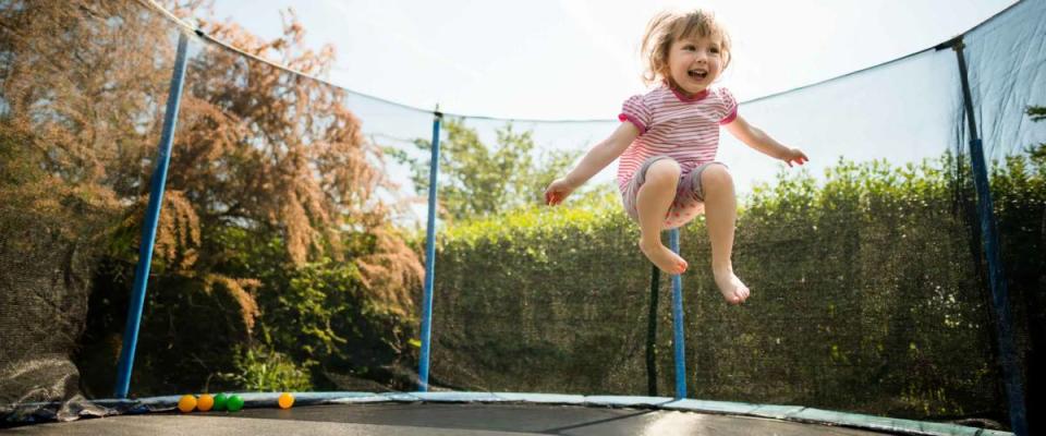 Little child enjoys jumping on trampoline - outside in backyard