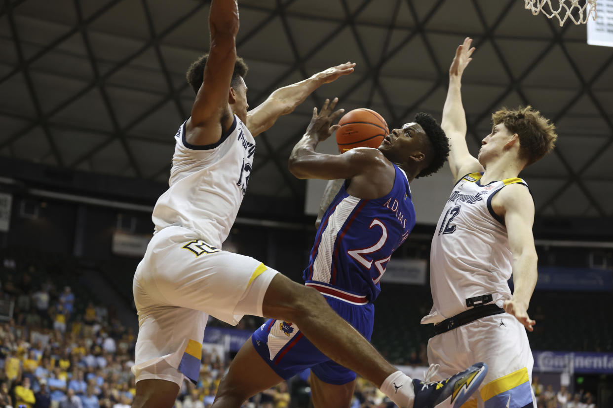 Kansas forward K.J. Adams Jr. (24) tries to go to the basket between Marquette forward Oso Ighodaro, left, and forward Ben Gold on Tuesday in Honolulu. (AP Photo/Marco Garcia)