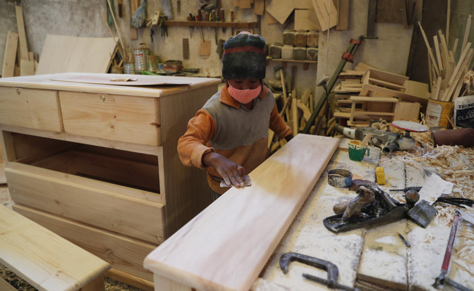 Yuri Delgado lija madera en el taller de carpintería de su familia en El Alto, Bolivia, el miércoles 2 de septiembre de 2020. El niño de 11 años estudia cada mañana antes de trabajar en el taller, después de que el año escolar fue cancelado en su país debido a la pandemia del nuevo coronavirus. (AP Foto/Juan Karita)