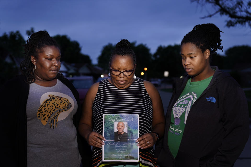 Michelle Branch, center, holds a pamphlet from the memorial service of her younger brother, Craig Elazer, 56, along with Elazer's stepdaughter, Shatia Jones, right, and niece, Alexa Sanders, in St. Louis on Monday, May 17, 2021. Elazer had struggled all his life with anxiety so bad his whole body would shake. But because he was Black, he was seen as unruly, not as a person who needed help, Branch says. He had started taking drugs to numb his nerves before he was old enough to drive a car. (AP Photo/Brynn Anderson)