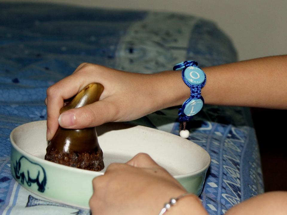 A woman grinds a rhino horn on a ceramic plate to get rhino horn powder at her home in Hanoi, Vietnam.