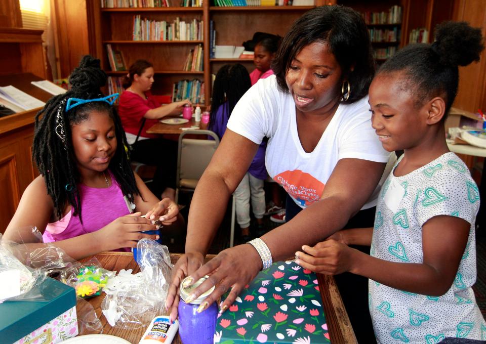 LaTasha Langdon (center) of Divine Destinies helps Princess Larry (right), 9, and Ericka Day-Griffin, 10, with their jars of positive affirmations and photo boxes for a class called 