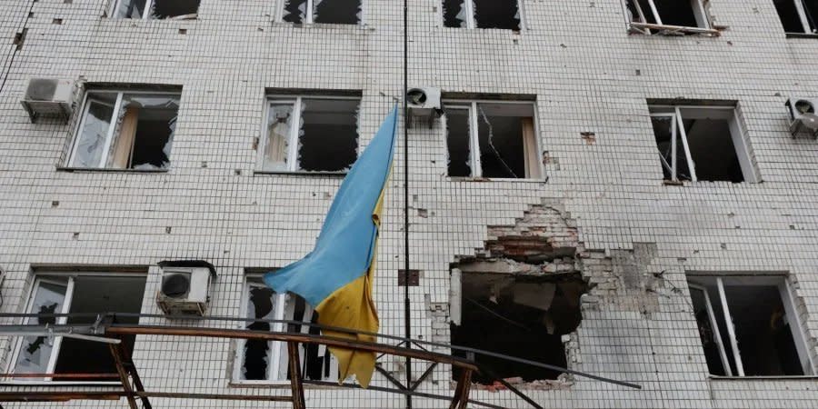 The Ukrainian flag in front of a building damaged by Russian shelling in Maryinka, Donetsk region, April 14, 2022