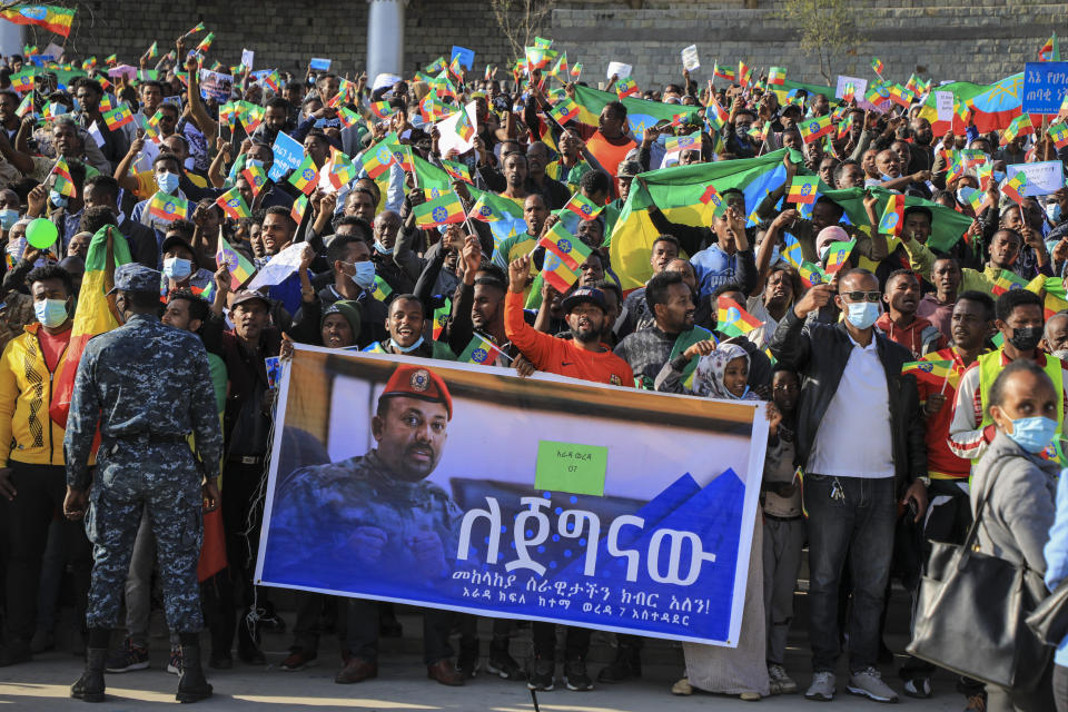 FILE - People gather behind a placard showing Prime Minister Abiy Ahmed at a rally organized by local authorities to show support for the Ethiopian National Defense Force (ENDF), at Meskel square in downtown Addis Ababa, Ethiopia Sunday, Nov. 7, 2021. Placard in Amharic reads: "We Have Respect For Our Brave National Army". Ethiopia's prime minister says he will lead his country's army "from the battlefront" beginning Tuesday, Nov. 23, 2021, a dramatic new step by the Nobel Peace Prize-winner in a devastating yearlong war. (AP Photo/File)