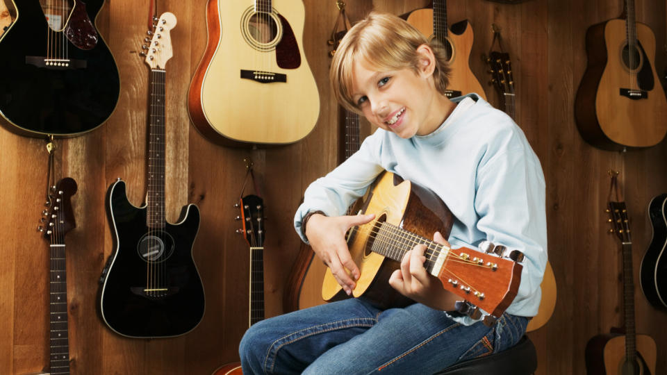 Kid in a guitar store playing an acoustic guitar