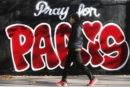 A man walks past recently-painted graffiti in Paris, November 15, 2015. REUTERS/Christian Hartmann