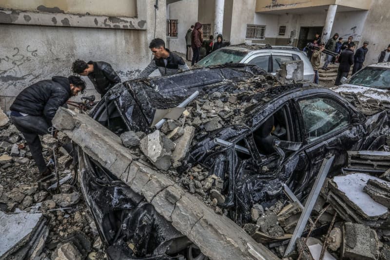 Palestinians inspect destroyed vehicles following an Israeli air attack. Abed Rahim Khatib/dpa