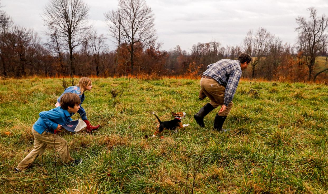 Sam Kennedy III, right, creep through the property to spot a buck while his children Sam Kennedy IV, left and Margaret Kennedy as well as their beagle, Whitey, follow his lead in Columbia, Tenn. on Nov. 29, 2022. 