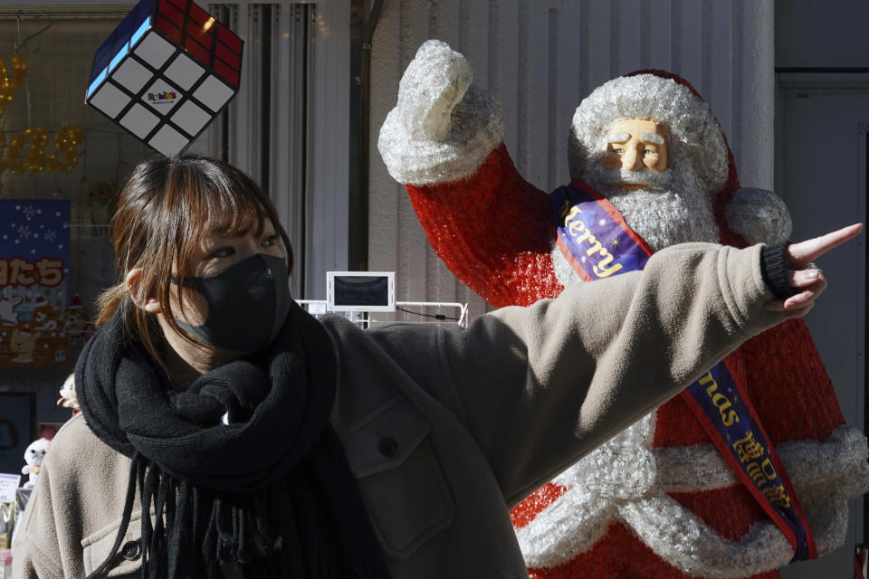 A woman wearing a protective mask to help curb the spread of the coronavirus gestures near a shop decoration depicting Saint Claus Thursday, Dec. 17, 2020, in Tokyo. The Japanese capital confirmed more than 800 new coronavirus cases on Thursday. (AP Photo/Eugene Hoshiko)