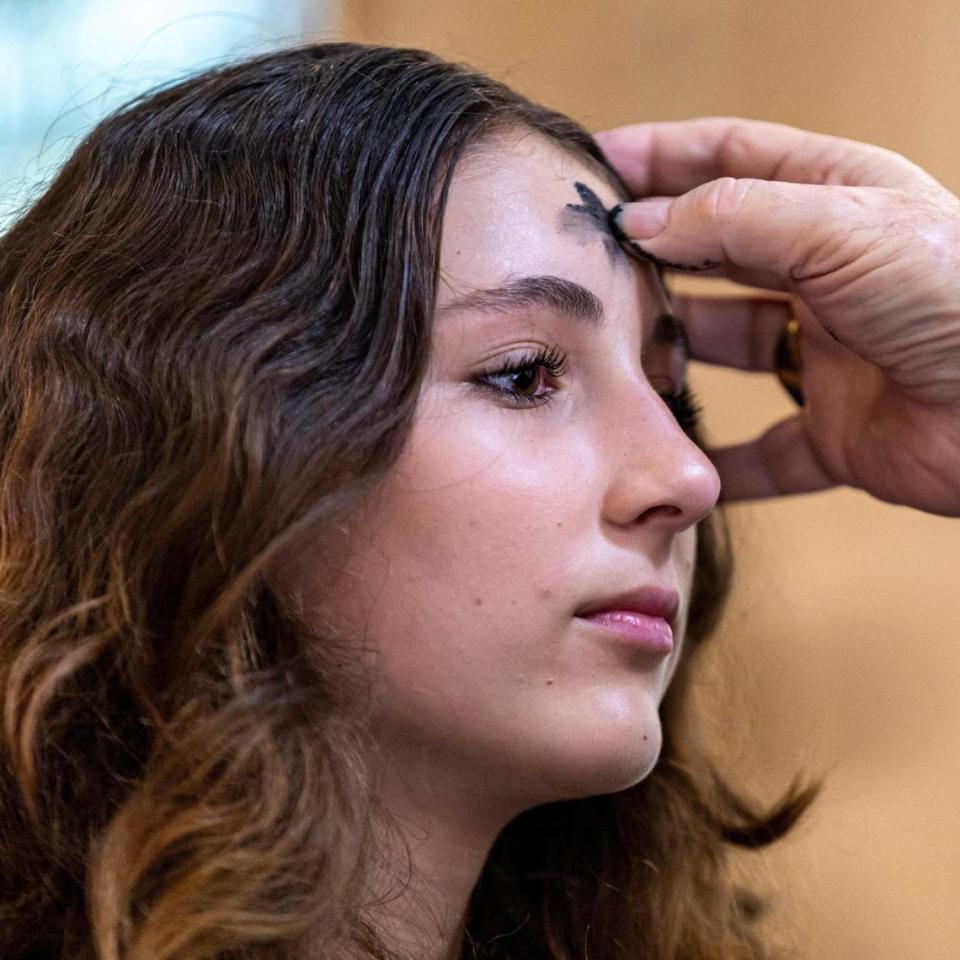 Archbishop Thomas Wenski draws a cross on a young woman’s forehead during an Ash Wednesday service in Miami.