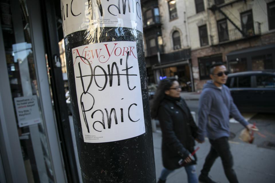 People walk past a convenient store where the latest cover of a magazine is stuck on a pillar outside of it on Sunday, March 15, 2020, in New York. President Donald Trump on Sunday called on Americans to cease hoarding groceries and other supplies, while one of the nation's most senior public health officials called on the nation to act with more urgency to safeguard their health as the coronavirus outbreak continued to spread across the United States. (AP Photo/Wong Maye-E)