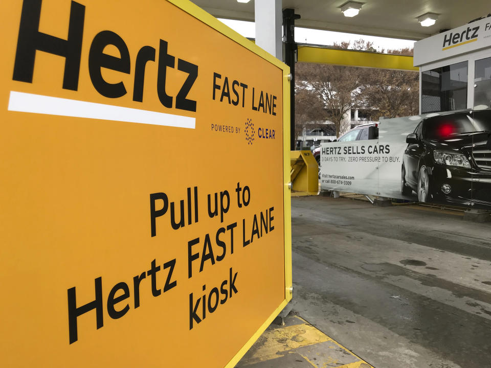 In this Friday, Dec. 7, 2018, photo, a Hertz "Fast Lane" sign directs rental car drivers to a biometric scanning machine at Hartsfield-Jackson Atlanta International Airport, in Atlanta. In a first for the rental car industry, Hertz is teaming up with Clear, the maker of biometric screening kiosks found at many airports and stadiums. Hertz says the partnership will slash the time it takes to pick up a rental car. (AP Photo/Jeff Martin)