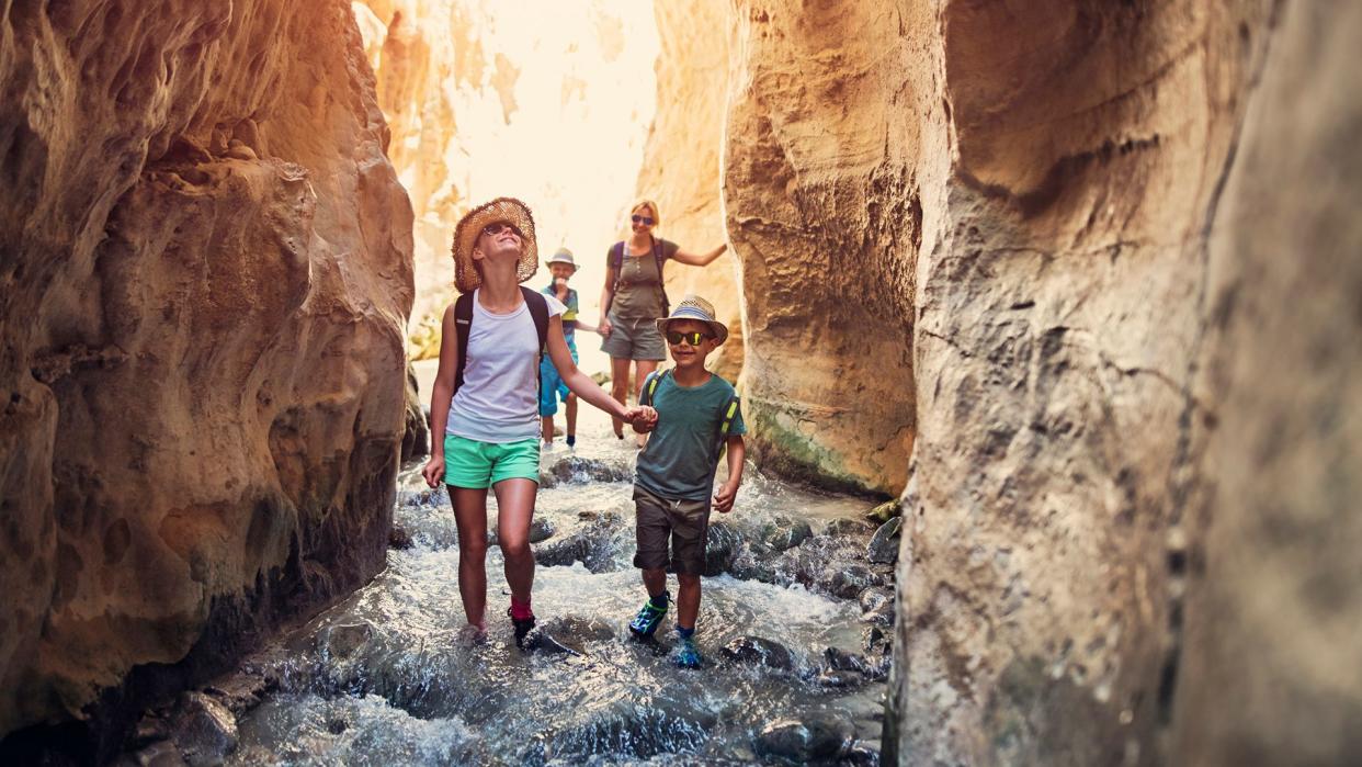 Mother and kids hiking through river Rio Chillar in Andalusia, Spain.