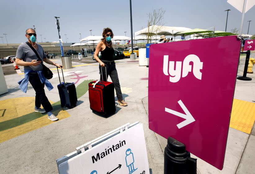 LAX AIRPORT, CA - AUGUST 20: Passengers make their way to the rideshare location at LAX as Uber and Lyft drivers held a moving rally as part of a statewide day of action to demand that both ride-hailing companies follow California law and grant drivers "basic employee rights" and to "denounce the corporations' efforts to avoid their responsibilities to workers." Uber and Lyft threatened to suspend services in California Thursday night but a court granted Uber and Left a stay to a preliminary injunction requiring both rideshare companies to reclassify their drivers as employees, meaning the rideshare companies will not suspend service in California tonight as they threatened. Los Angeles on Thursday, Aug. 20, 2020 in LAX Airport, CA. (Al Seib / Los Angeles Times