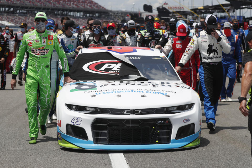 Nascar drivers Kyle Busch, left, and Corey LaJoie, right, join other drivers and crews as they push the car of Bubba Wallace to the front of the field prior to the start of the NASCAR Cup Series auto race at the Talladega Superspeedway in Talladega Ala., Monday June 22, 2020. In an extraordinary act of solidarity with NASCAR’s only Black driver, dozens of drivers pushed the car belonging to Bubba Wallace to the front of the field before Monday’s race as FBI agents nearby tried to find out who left a noose in his garage stall over the weekend. (AP Photo/John Bazemore)