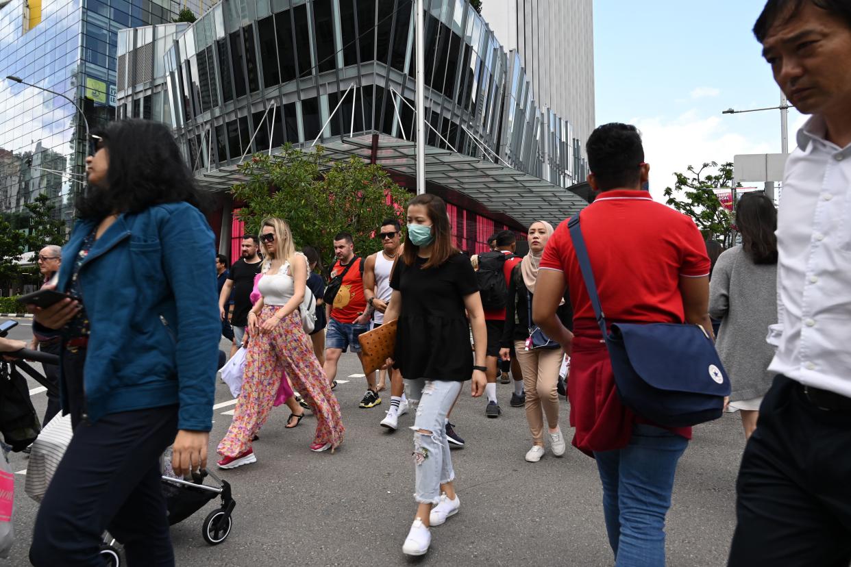 A woman wearing a protective facemask amid fears about the spread of the COVID-19 coronavirus crosses the road in Singapore on February 26, 2020. (Photo by ROSLAN RAHMAN / AFP) (Photo by ROSLAN RAHMAN/AFP via Getty Images)