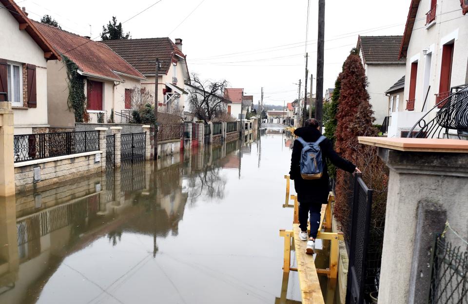 <p>A woman walks on a makeshit elevated track set to help inhabitants reach their home in a flooded street on Jan. 30, 2018, in Villeneuve-Saint-Georges, near Paris. (Photo: Alain Jocard/AFP/Getty Images) </p>