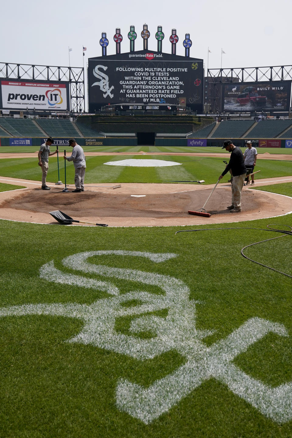 The Guaranteed Rate Field grounds crew work around home plate after a baseball game between the Chicago White Sox and the Cleveland Guardians was postponed due to multiple positive COVID-19 tests within the Guardians organization after Wednesday, May 11, 2022, in Chicago. (AP Photo/Charles Rex Arbogast)