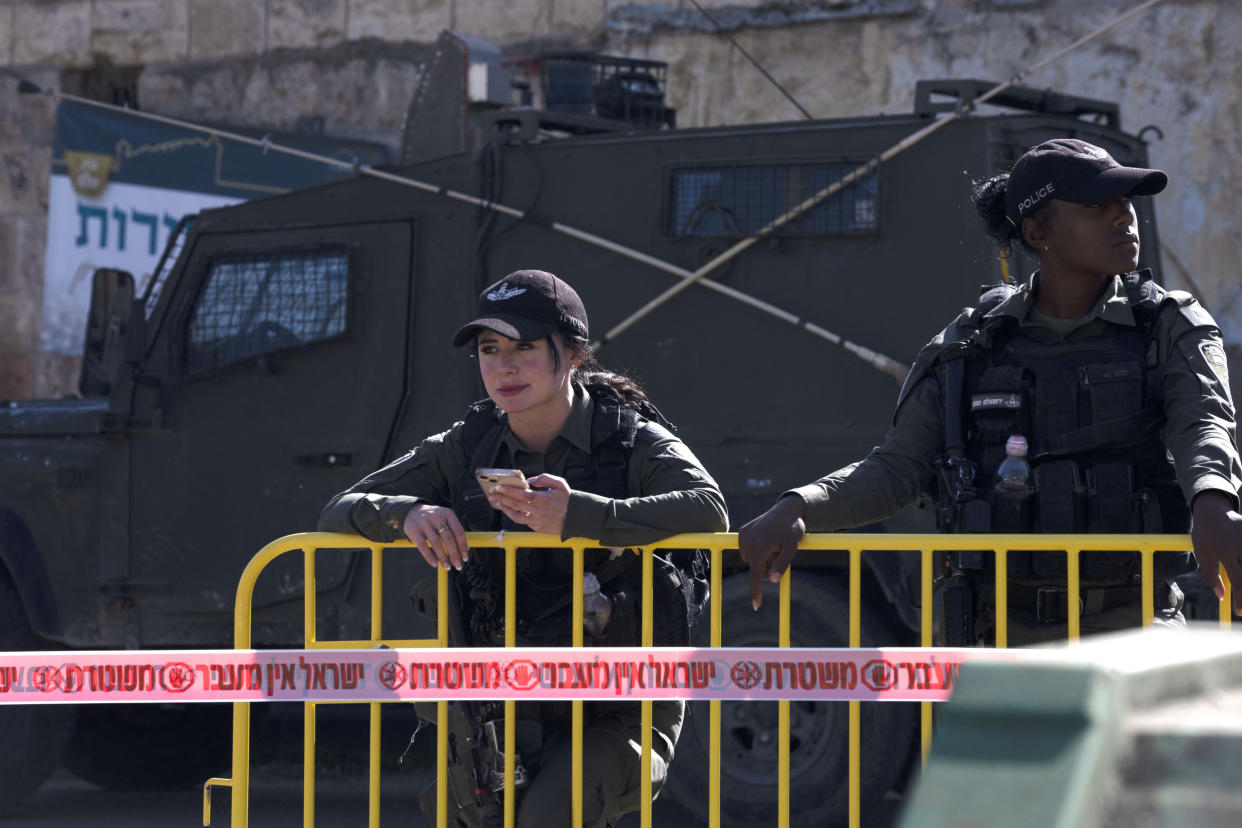 Israeli policewomen watch activists on a "solidarity tour" of the embattled West Bank city of Hebron, Friday, Dec. 2, 2022. Israeli peace activists toured the occupied West Bank's largest city Friday in a show of solidarity with Palestinians, amid chants of "shame, shame" from ultra-nationalist hecklers. The encounter in the center of Hebron signaled the widening rift among Israelis over the nature of their society and Israel's open-ended military rule over the Palestinians, now in its 56th year. (AP Photo/ Maya Alleruzzo)