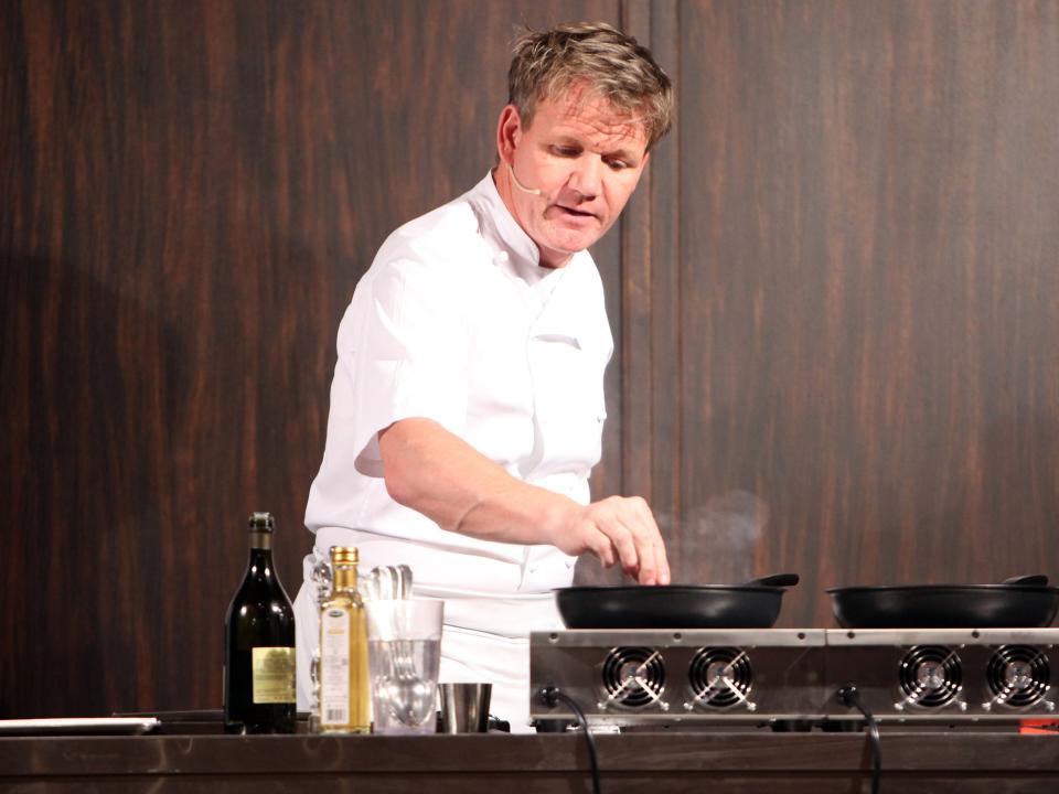 Gordon Ramsay cooking at a stoke with heated pans.