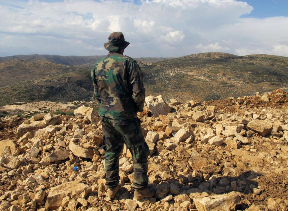 FILE - In this May 9, 2015 file photo, a Hezbollah fighter looks toward Syria while standing in the fields of the Lebanese border village of Brital, Lebanon. Aleppo is set to be recaptured by Syrian President Bashar Assad, but the victory will not be Assad's alone. The battle for Syria's largest city has attracted thousands of foreign forces, including Russian soldiers and thousands of fighters from Iran, Lebanon, Iraq and Afghanistan. (AP Photo/Bassem Mroue, File)