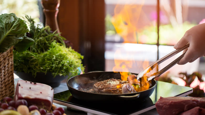 Flambé meat in a pan on portable stove