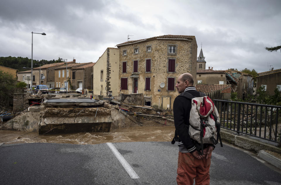 A man watches a damaged bridge over a torrent after flash floods in the town of Villegailhenc, southern France, Monday, Oct.15, 2018. Flash floods tore through towns in southwest France, turning streams into raging torrents that authorities said killed several people and seriously injured at least five others. (AP Photo/Fred Lancelot)