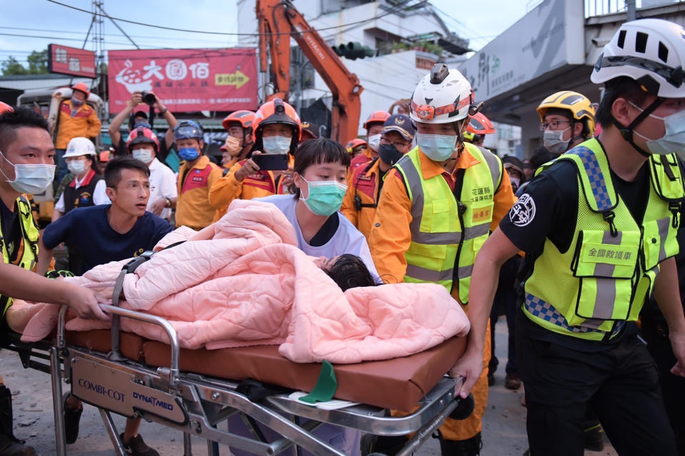 In this photo provided by Hualien City Government, a trapped victim is carried on a stretcher as the victim was found and rescued by firefighters from a collapsed building in Yuli township, Hualien County, eastern Taiwan, Sunday, Sept. 18, 2022. A strong earthquake shook much of Taiwan on Sunday, toppling at least one building and trapping two people inside and knocking part of a passenger train off its tracks at a station.(Hualien City Government via AP)