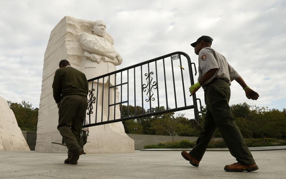 National Park workers remove a barricade at the Martin Luther King Jr. Memorial as it reopens to the pubic in Washington October 17, 2013. The White House moved quickly early on Thursday to get the U.S. government back up and running after a 16-day shutdown, directing hundreds of thousands of workers to return to work. REUTERS/Kevin Lamarque